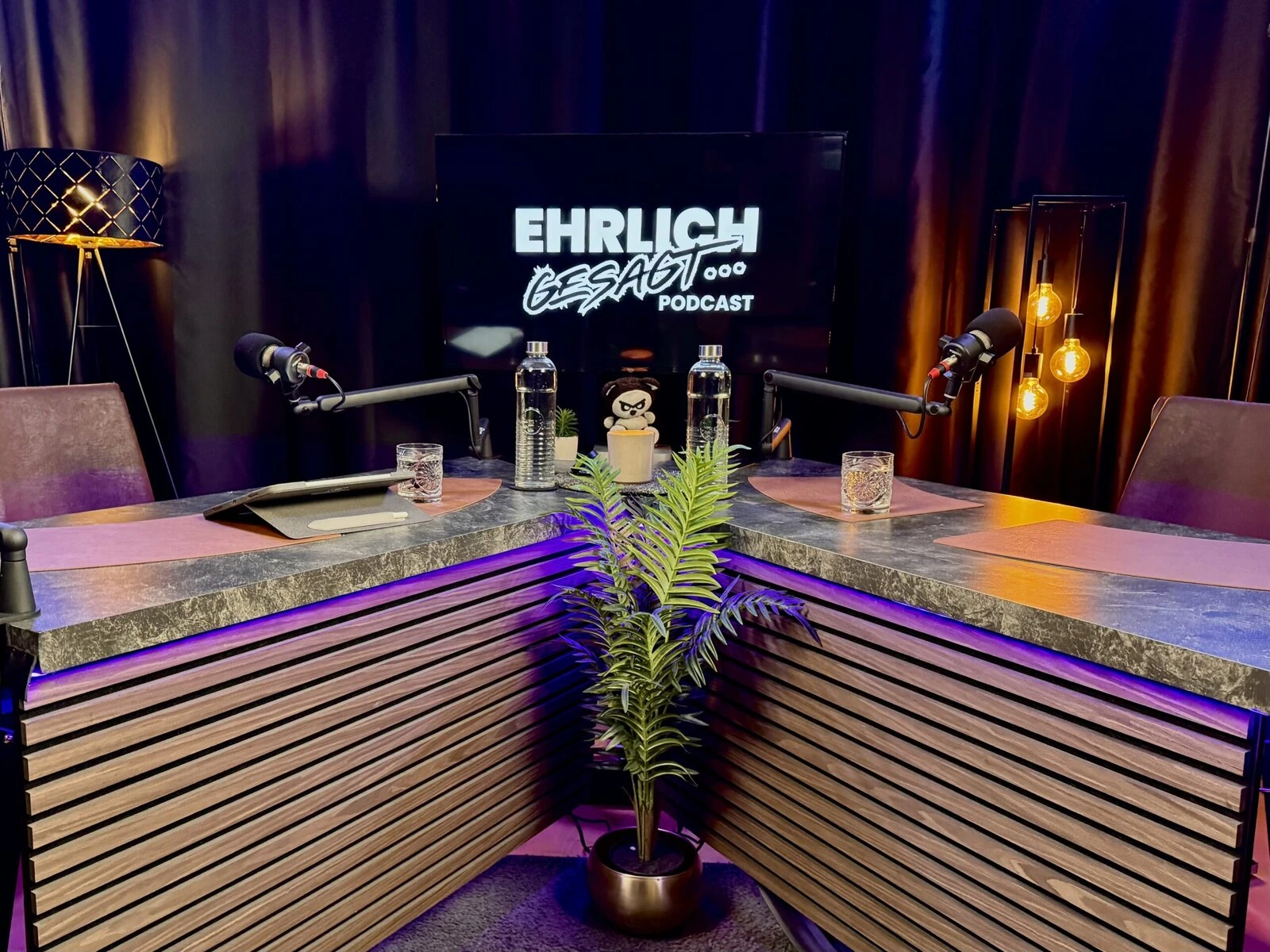 podcast-studio-linz Moderner Podcast-Studiosetup mit Mikrofonen und Fernseher, ideal für Social Media & Podcast Marketing.