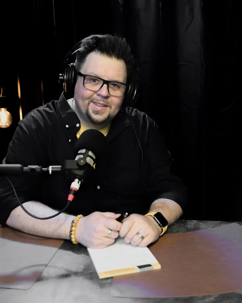 Experte bei TheAngryTeddy Mann mit Kopfhörern spricht in Mikrofon bei Podcastaufnahme.