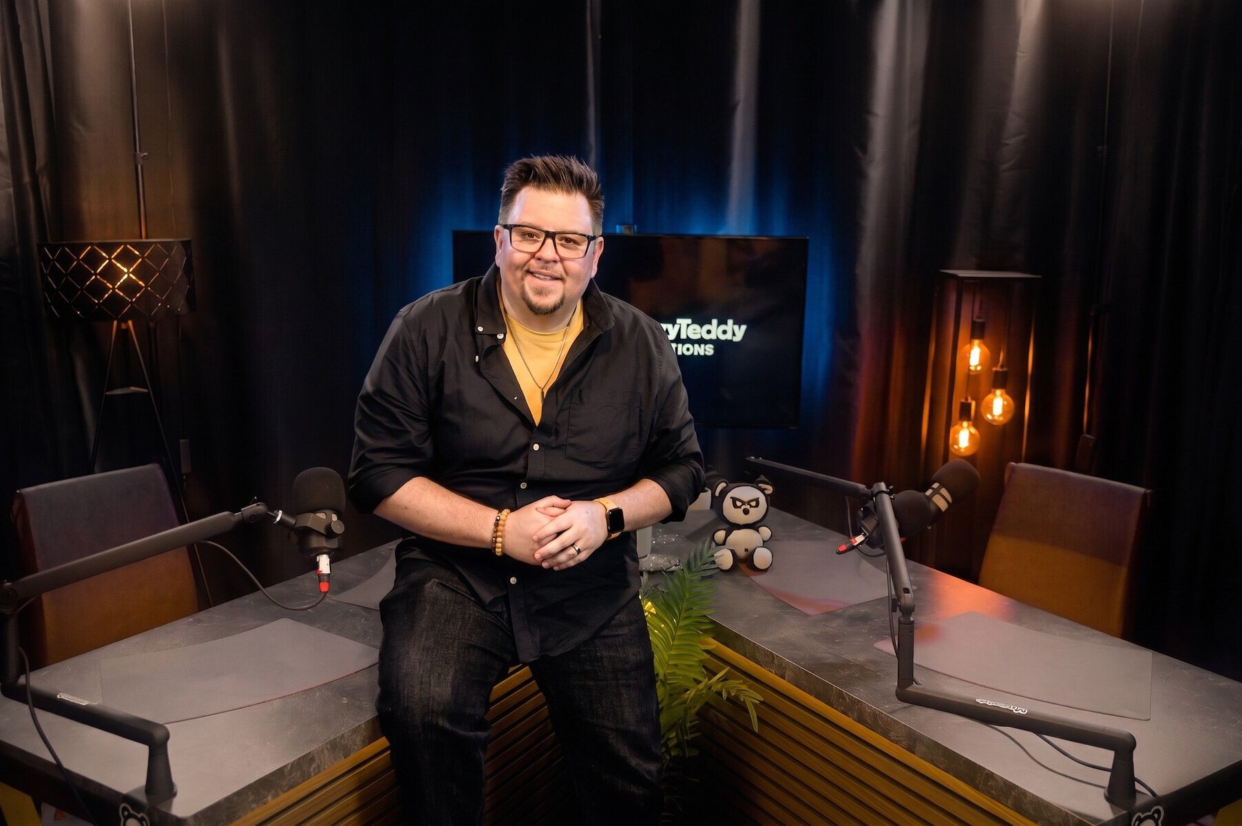 daniel-friesenecker-podcast-studio Mann im Aufnahmestudio mit Mikrofonen und Teddy, bereit für Social Media & Podcast-Aufnahmen.